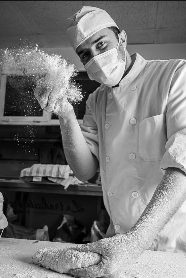 Dueño de El Panazo Madrid amasando pan artesanal con destreza en la panadería.