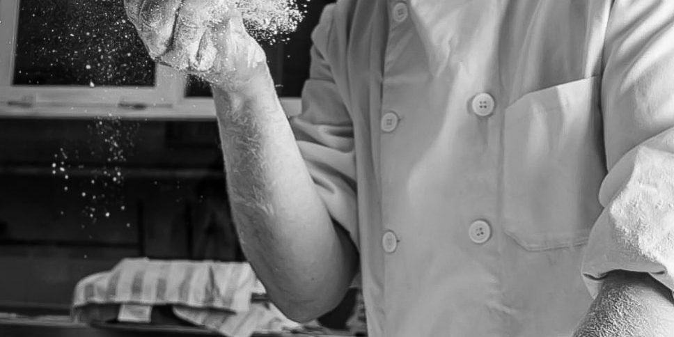 Dueño de El Panazo Madrid amasando pan artesanal con destreza en la panadería.